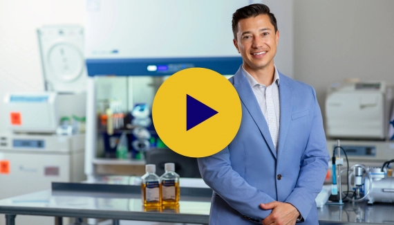person smiling with medical lab in background with play button on top